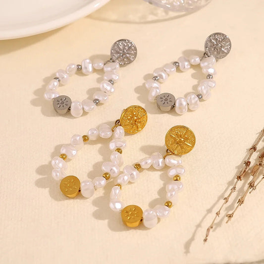 Two pair of pearl earrings with gold and silver accents on a beige surface