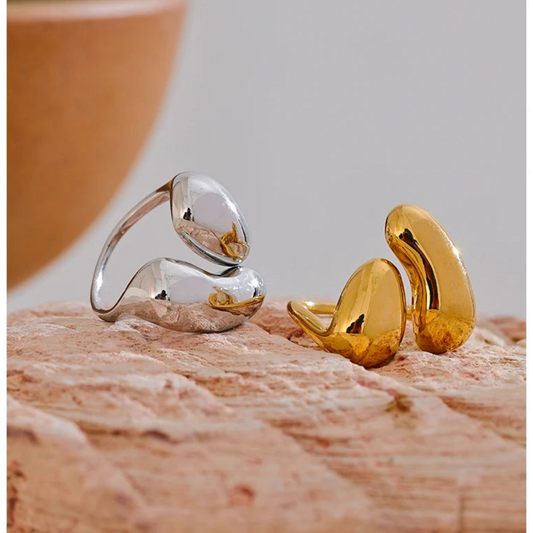 PVD gold-plated and silver earrings on a textured surface with a blurred background