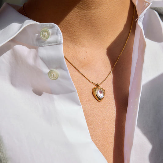 Model wearing Bianca Crystal Heart Pendant Necklace — luminous crystal and gold chain styled at collarbone.”