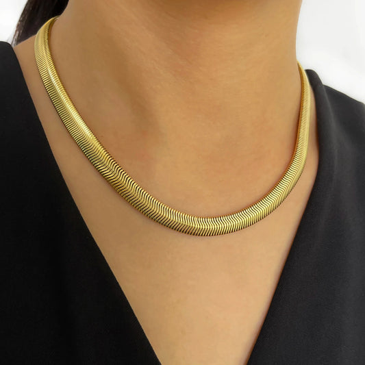 Gold necklace worn by a person against a black background