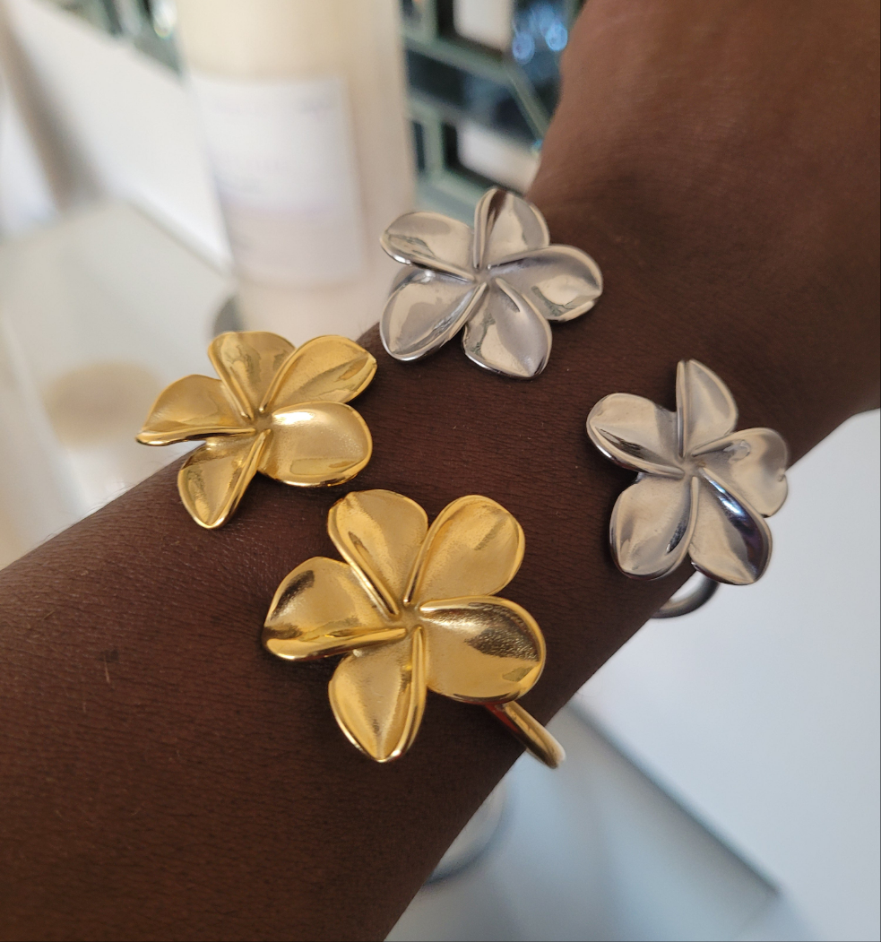 Gold and silver flower-shaped bracelets on a model's wrist.