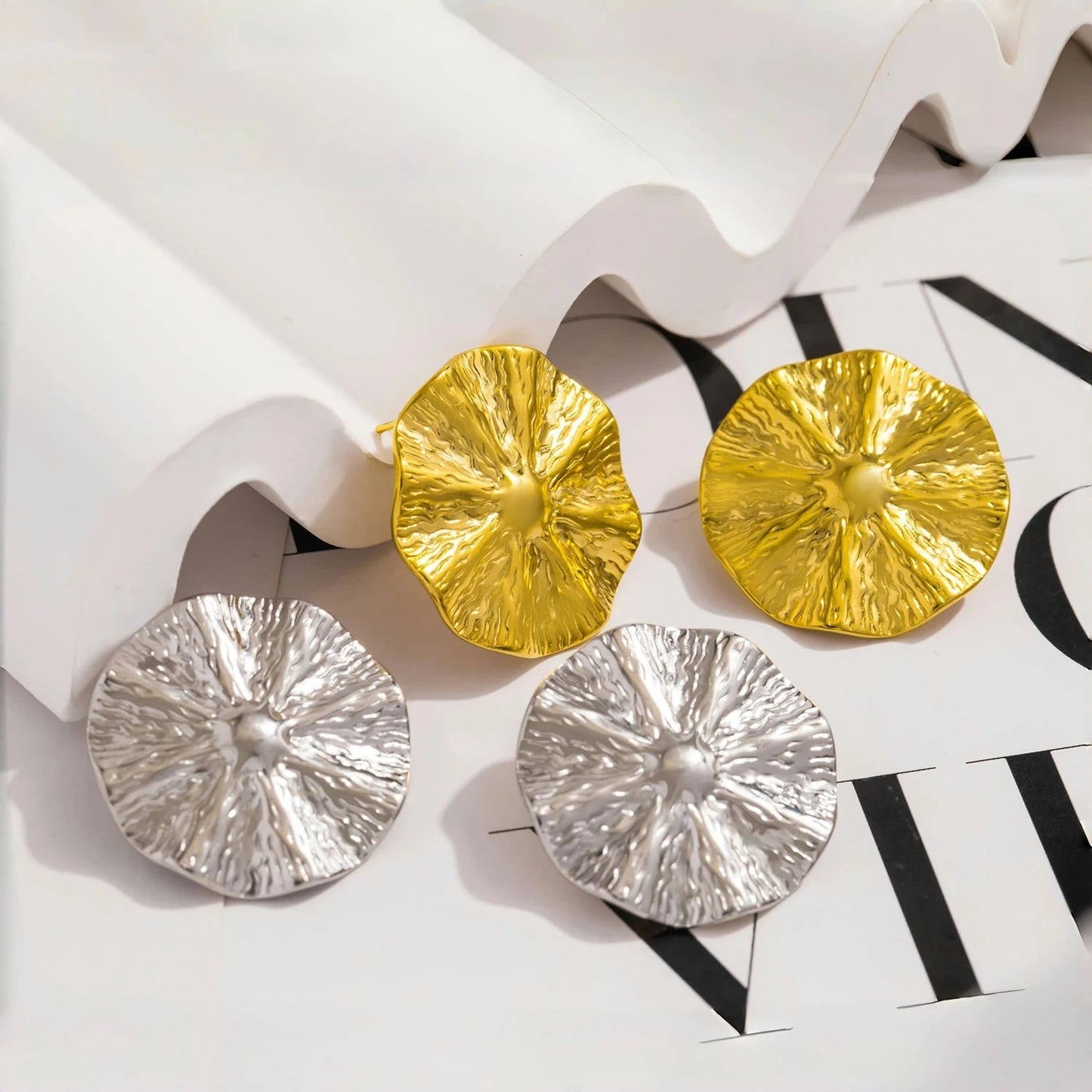 Gold and silver round earrings on a magazine page. Rebecca Bloom