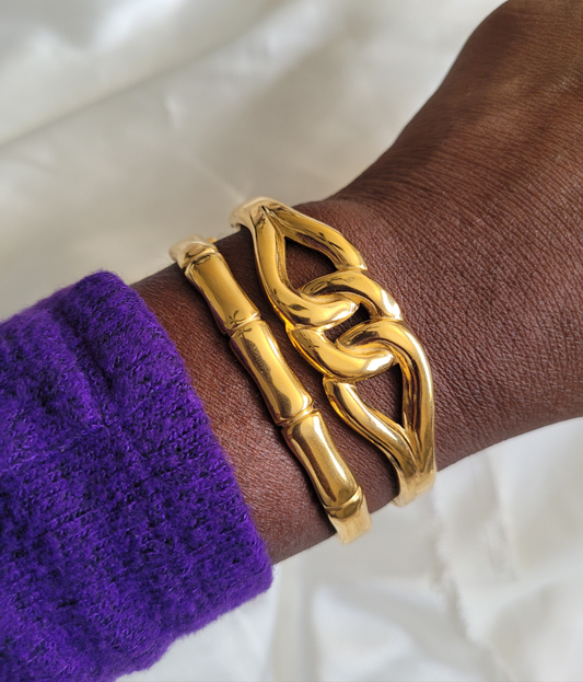 Fashion 18K PVD gold bracelet on a wrist with a purple sleeve against a white background