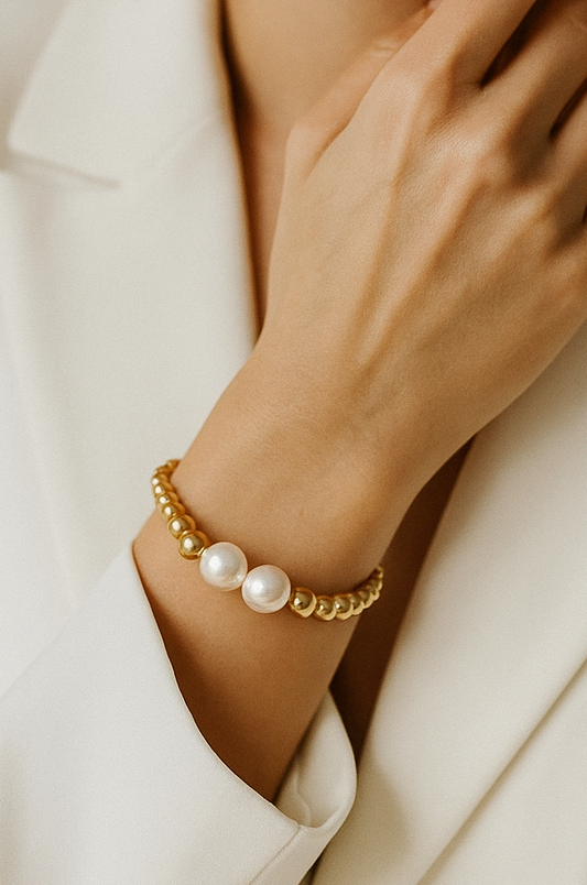 Gold bracelet with pearls on a model in a white suite