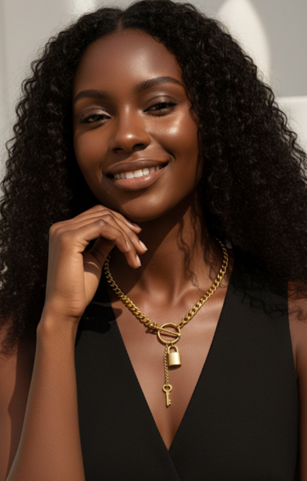 Woman wearing a gold necklace with a lock and key pendant, smiling.