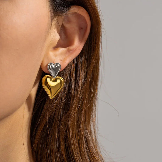 Model wearing Mixed Metal Heart Drop Earrings styled with a neutral blouse for everyday elegance