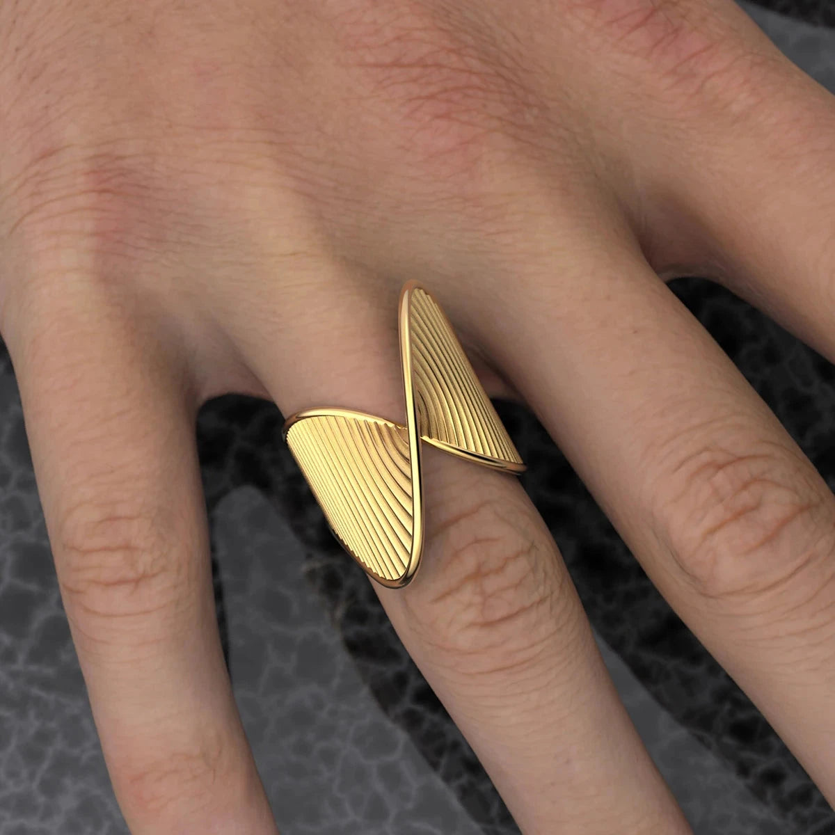 18K PVD Gold-Plated triangular ring on a finger with a dark textured background. Minimalist bold women's ring