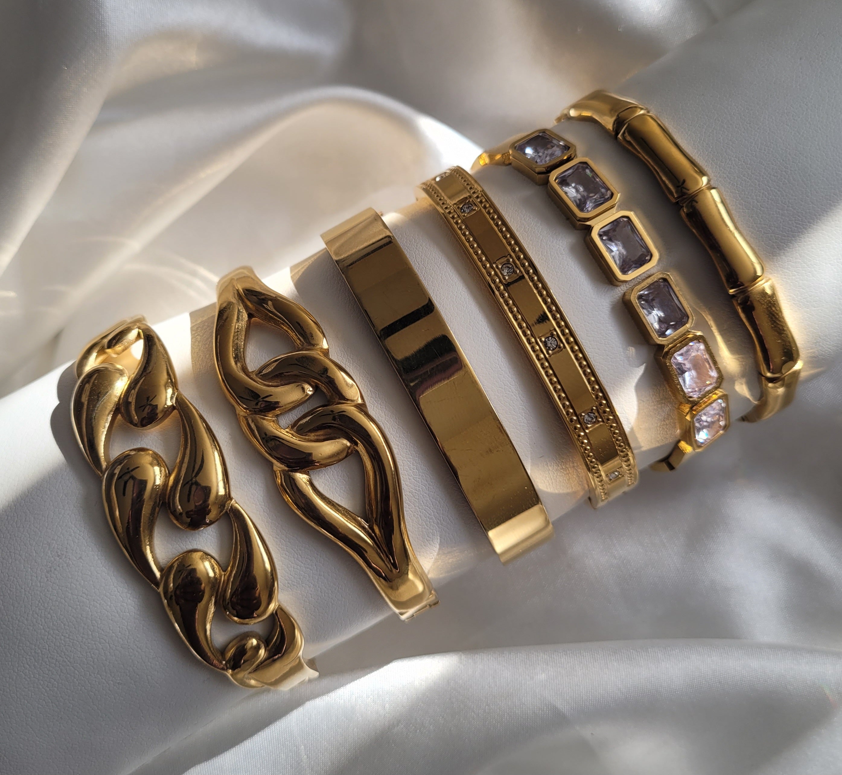 Set of gold bracelets on a white fabric background