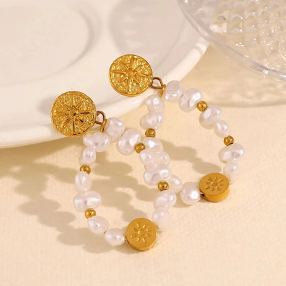 Pair of gold and pearl earrings on a beige surface