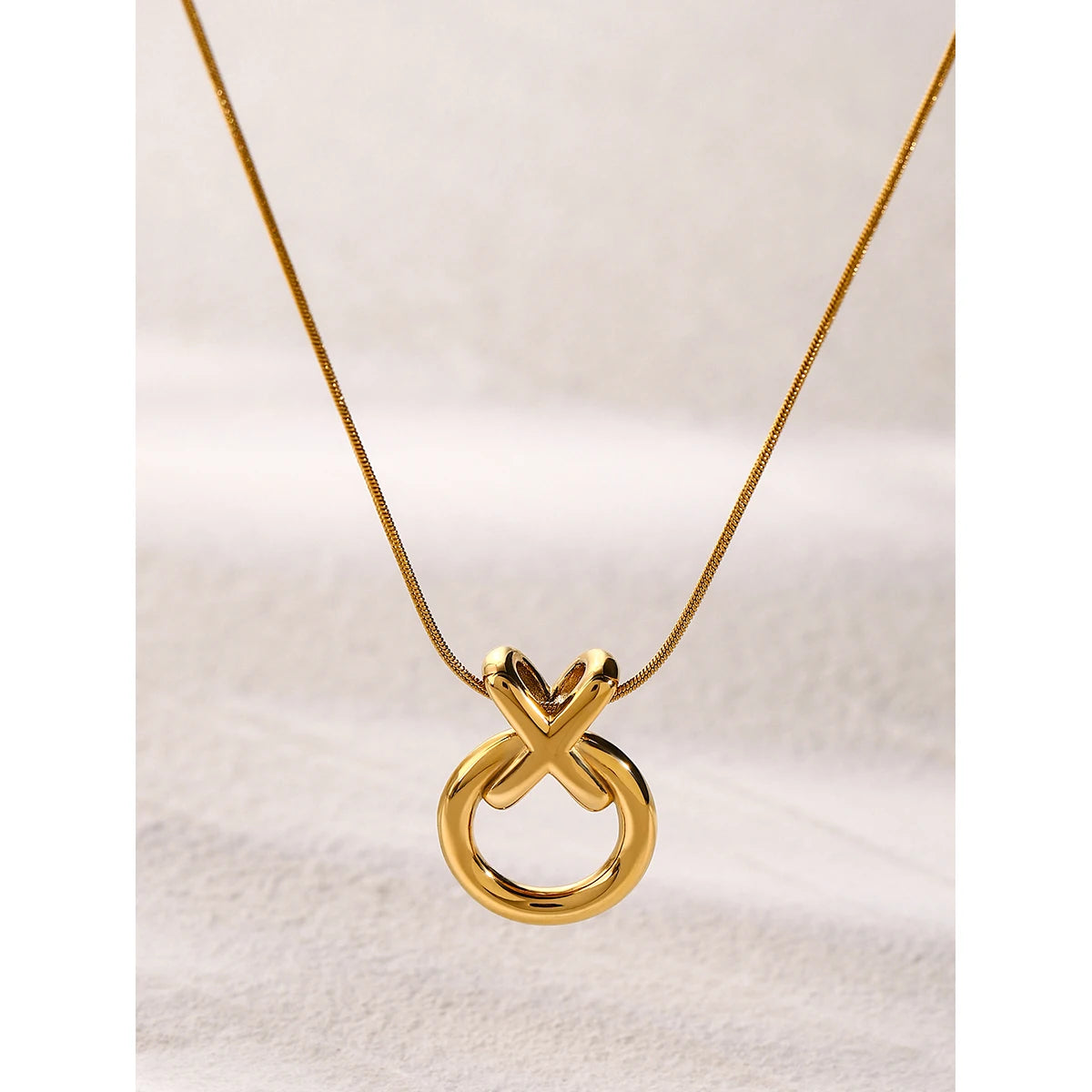  XO pendant necklace in gold, hanging from a snake chain link.