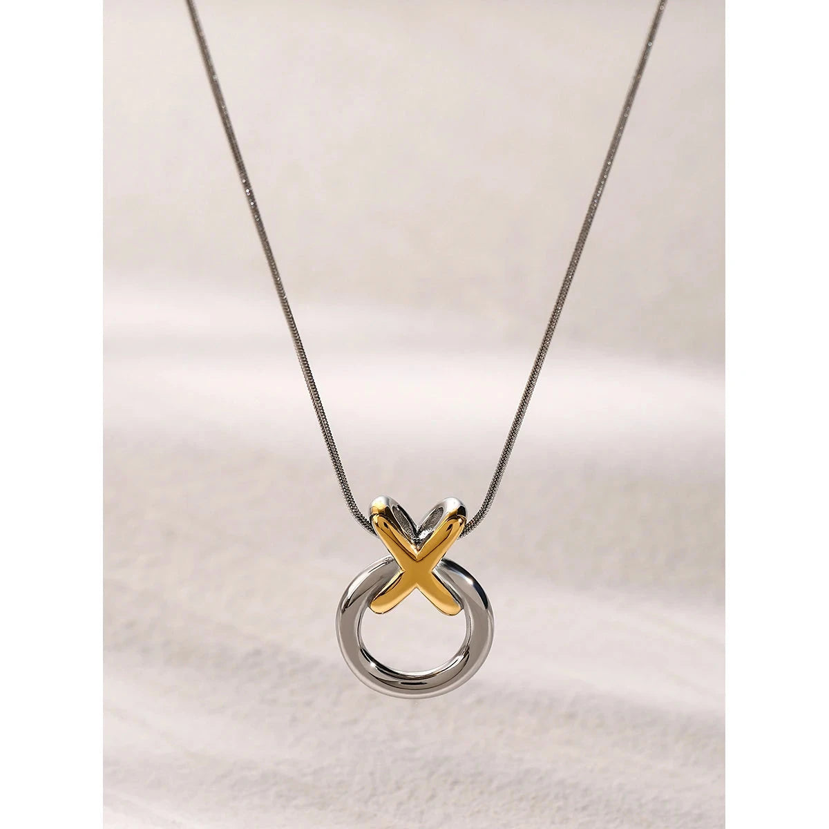 Necklace with a unique pendant featuring a gold 'X' 