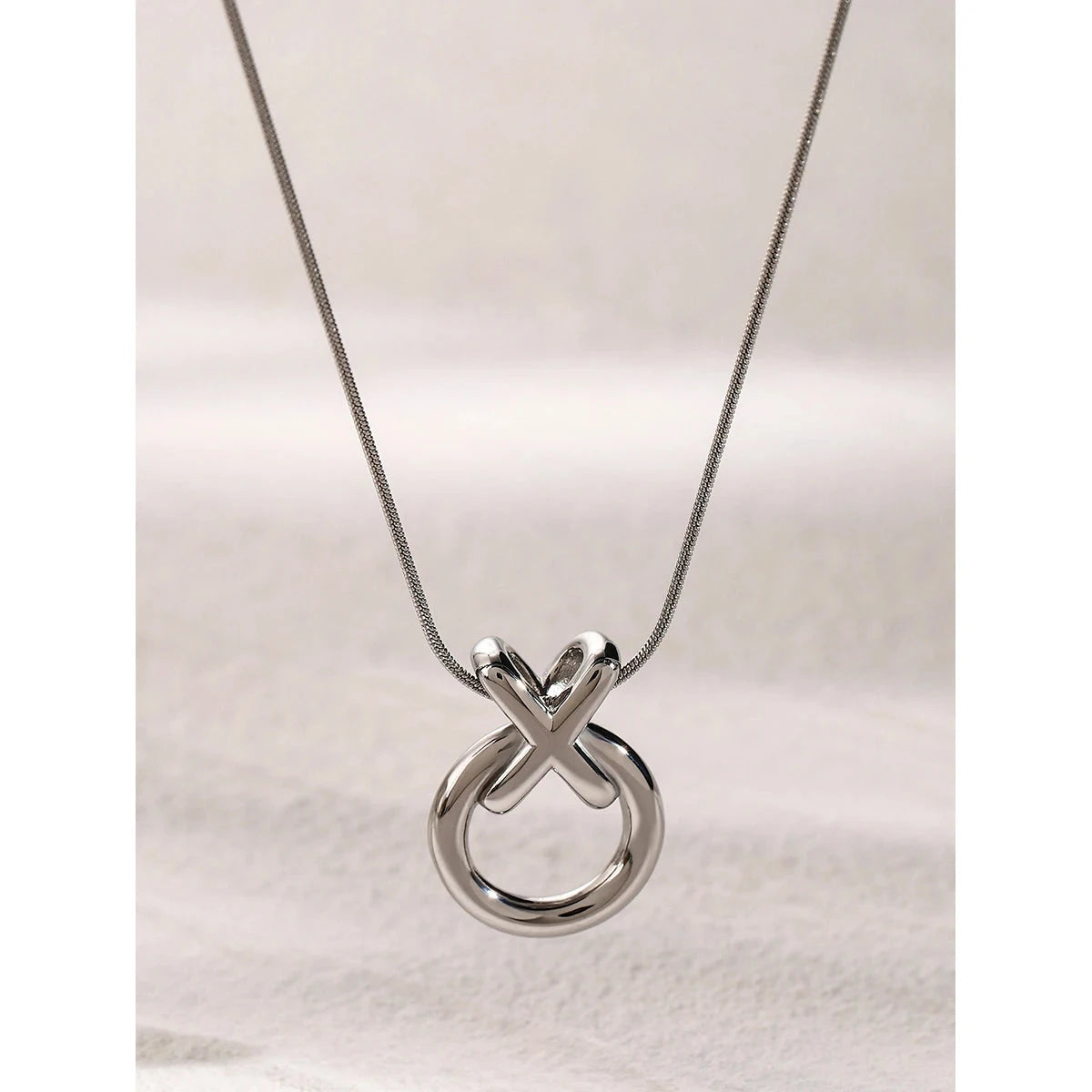 Silver stainless steel necklace with a XO unique pendant on a light background