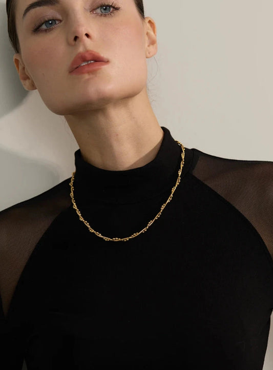 Woman wearing a gold necklace Water-resistant and tarnish-resistant against a neutral background