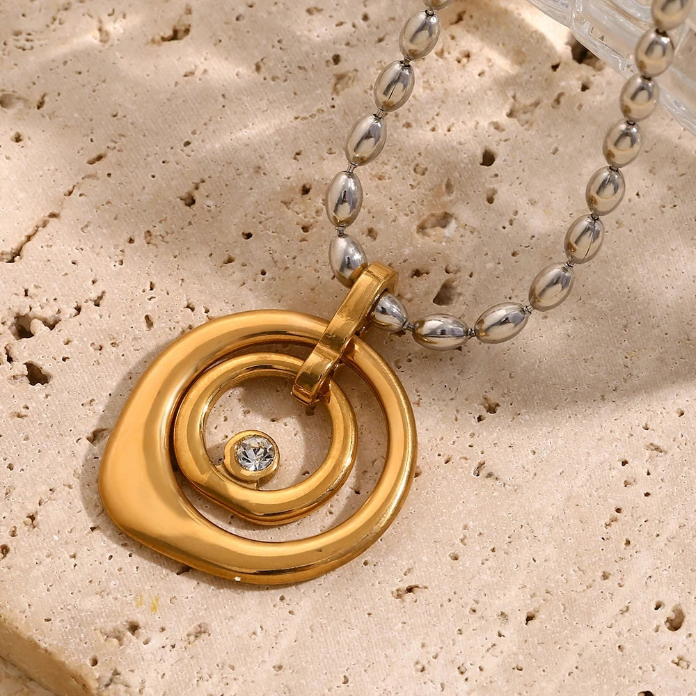 Gold spiral pendant with a cubic a zirconia on a textured beige surface