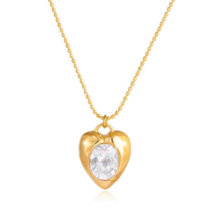 Gold heart-shaped necklace with a clear gemstone on a white background