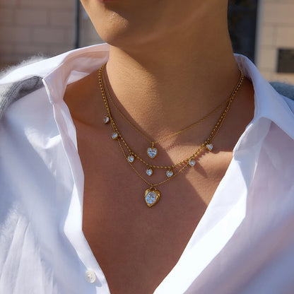 Necklace with heart-shaped pendant worn by a person in a white shirt.