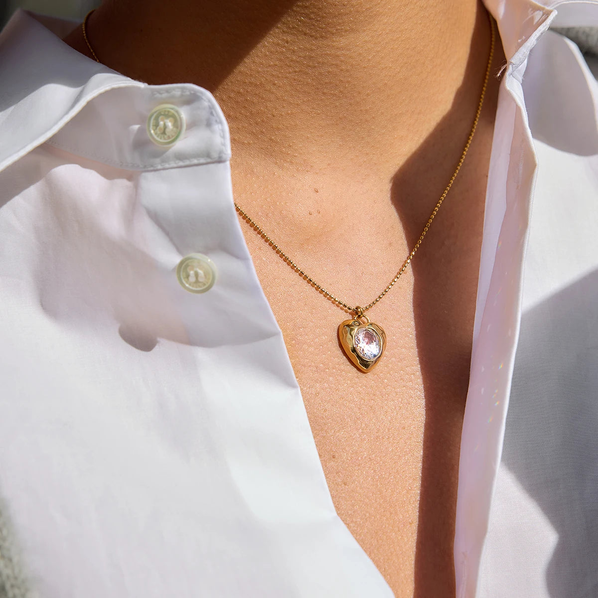 Model wearing Bianca Crystal Heart Pendant Necklace — luminous crystal and gold chain styled at collarbone.”