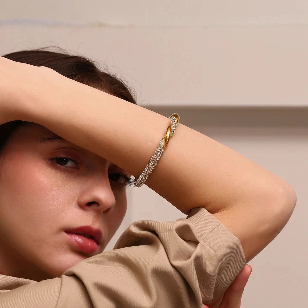 Woman wearing a 18k PVD gold plated open cuff bracelet with a neutral background