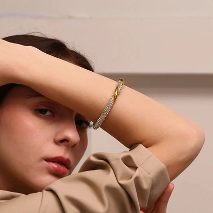 Woman wearing a 18k PVD gold plated open cuff bracelet with a neutral background