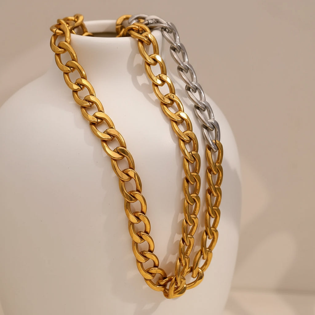 Two gold and silver chain necklaces on a wooden surface