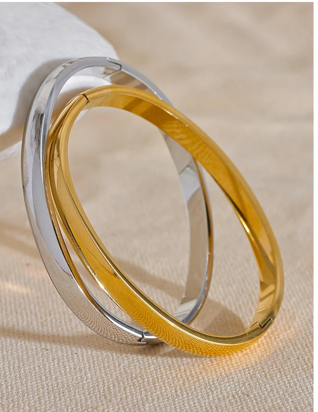 Two gold and silver fashio bangles on a beige fabric background  bangles