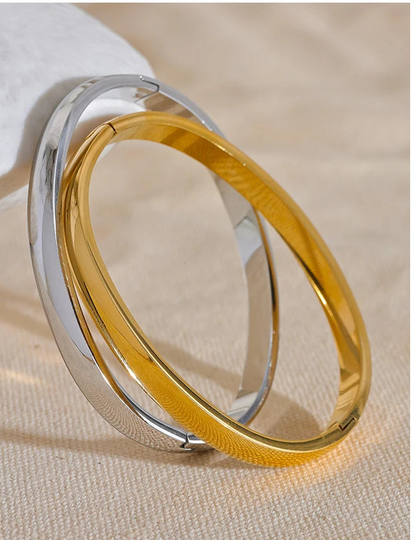 Two gold and silver fashio bangles on a beige fabric background  bangles