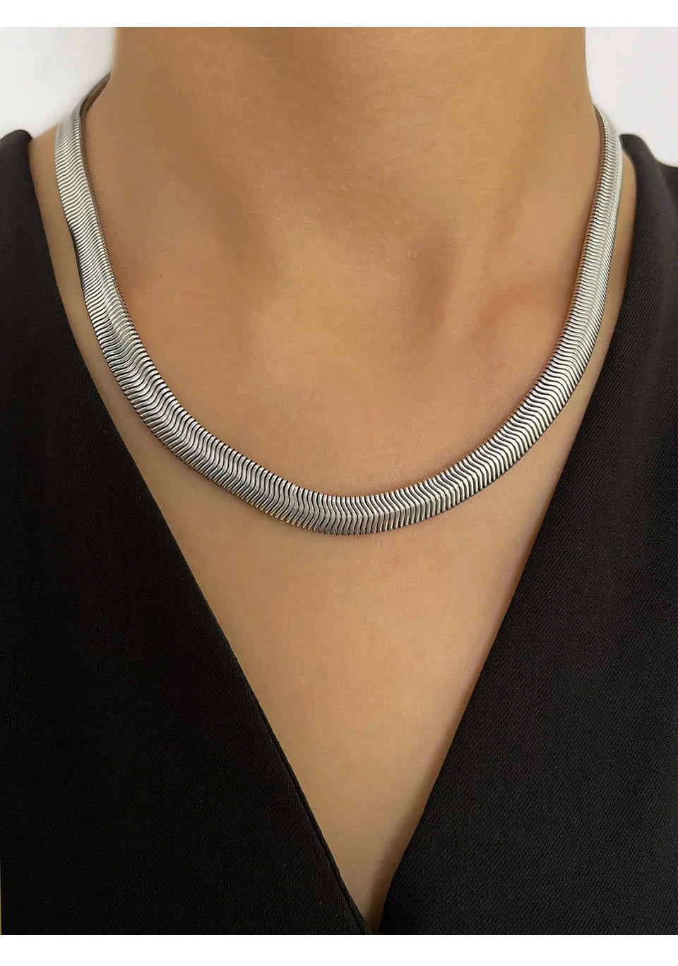 Silver fashion necklace on a woman wearing a black top against a white background
