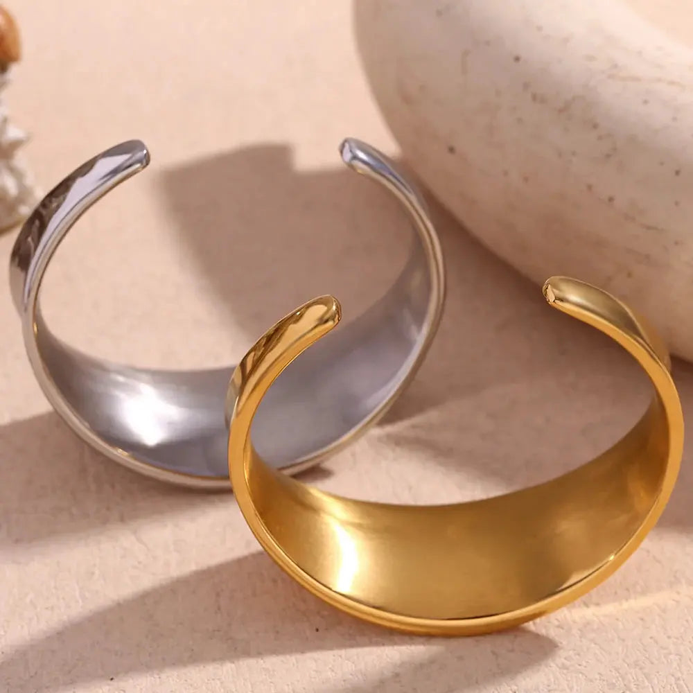 Gold and silver open cuffs on a beige surface