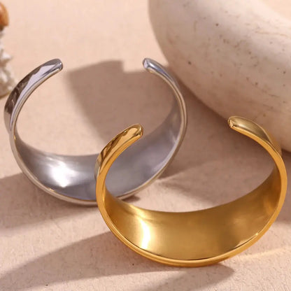 Gold and silver open cuffs on a beige surface