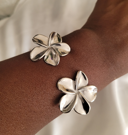 Silver flower-shaped bracelet on model's wrist against a neutral background