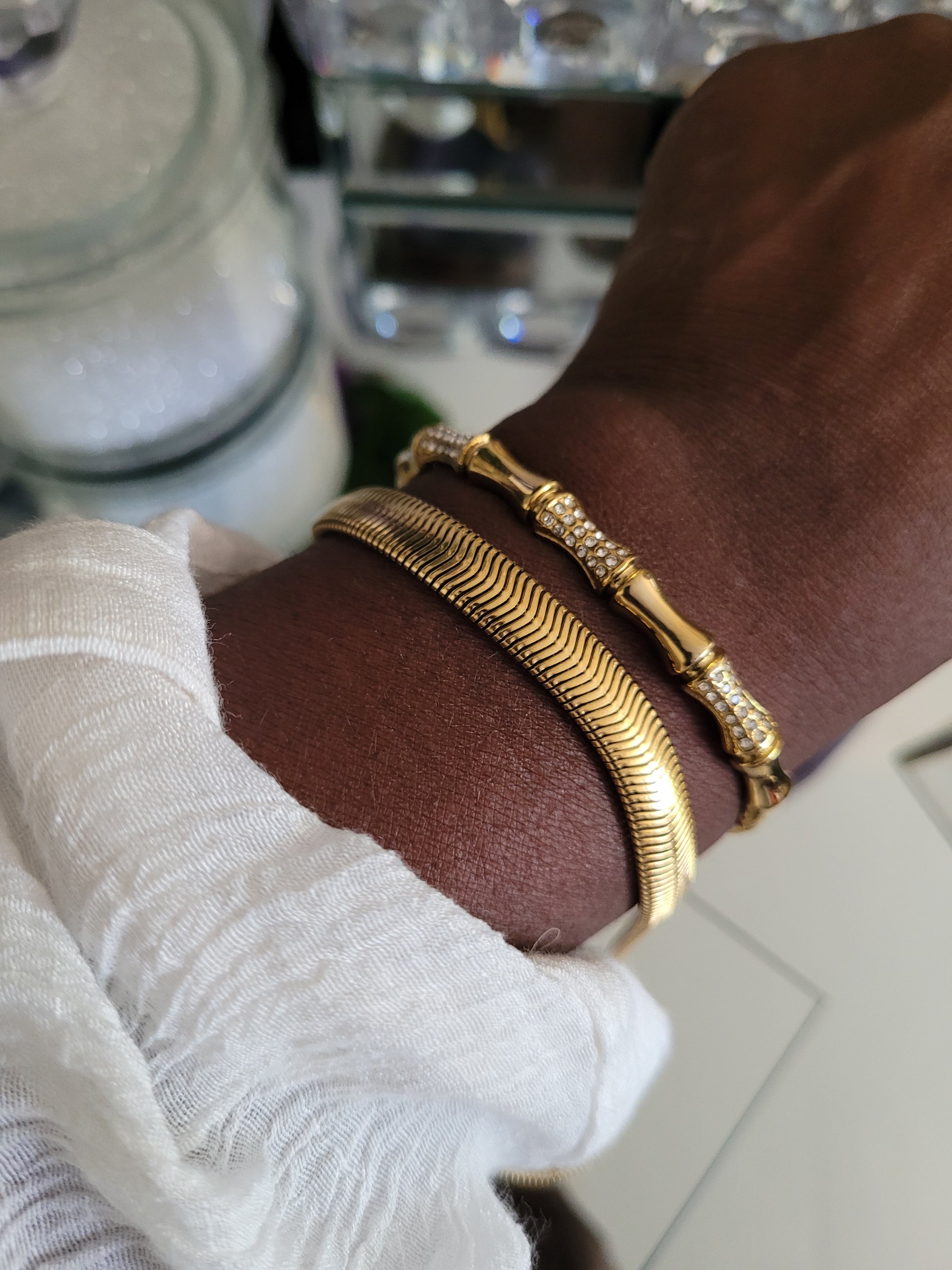 Gold bracelets on a wrist with a blurred background