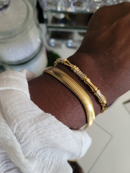 Gold bracelets on a wrist with a blurred background