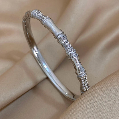 Silver Stainless steel fashion bracelet with bamboo design on a beige fabric background
