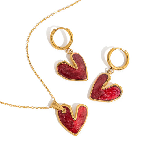 Jewelry set with red heart-shaped pendants on gold chains against a white background