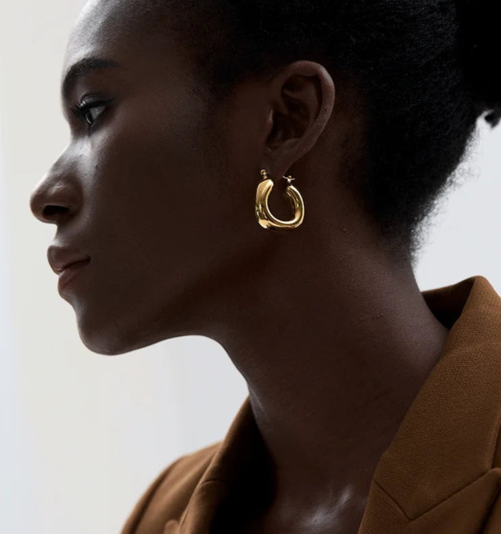 Woman wearing gold hoop earrings with a neutral background