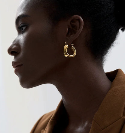 Woman wearing gold hoop earrings with a neutral background