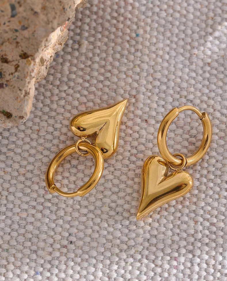 Gold heart-shaped hoop earrings on a textured surface