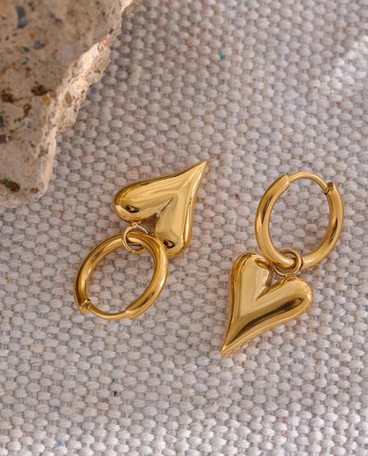 Gold heart-shaped hoop earrings on a textured surface