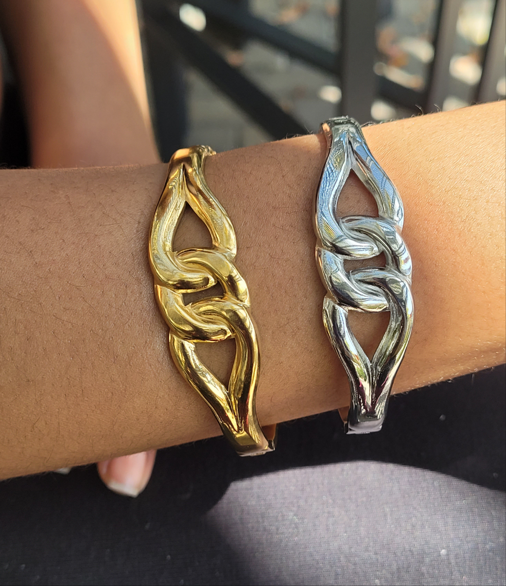 Gold and silver bracelets on a wrist with a blurred background