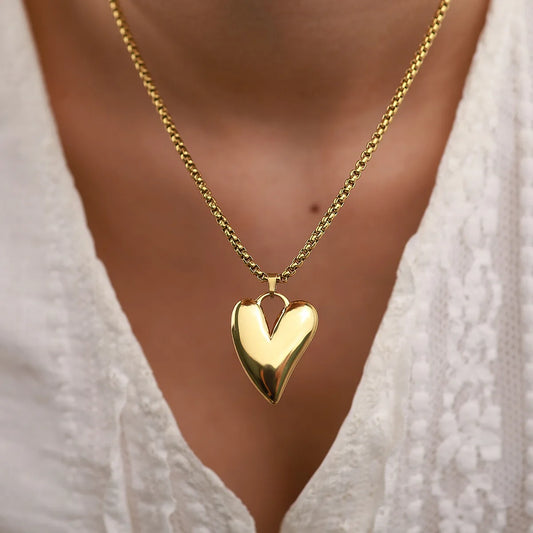 Gold heart-shaped necklace worn by a person with a blurred background