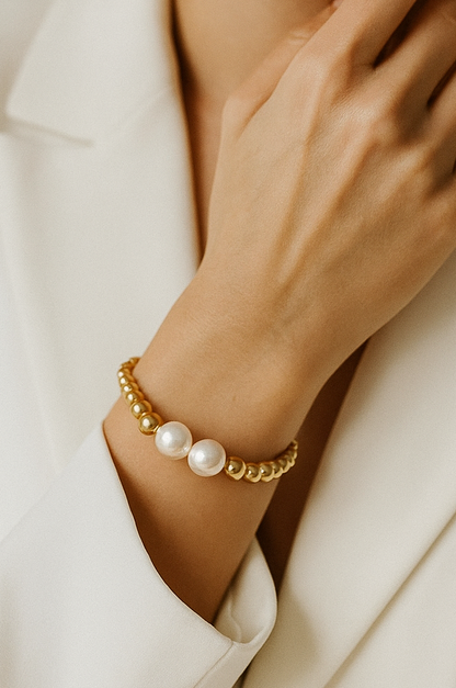 Gold bracelet with pearls on a model in a white suite