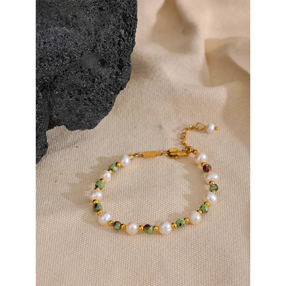 vintage statement bracelet with pearls and green stones on a beige surface