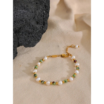 vintage statement bracelet with pearls and green stones on a beige surface