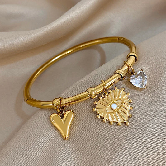 Close-up of Melinda evil eye and heart bracelet showing polished gold finish and detailed charms