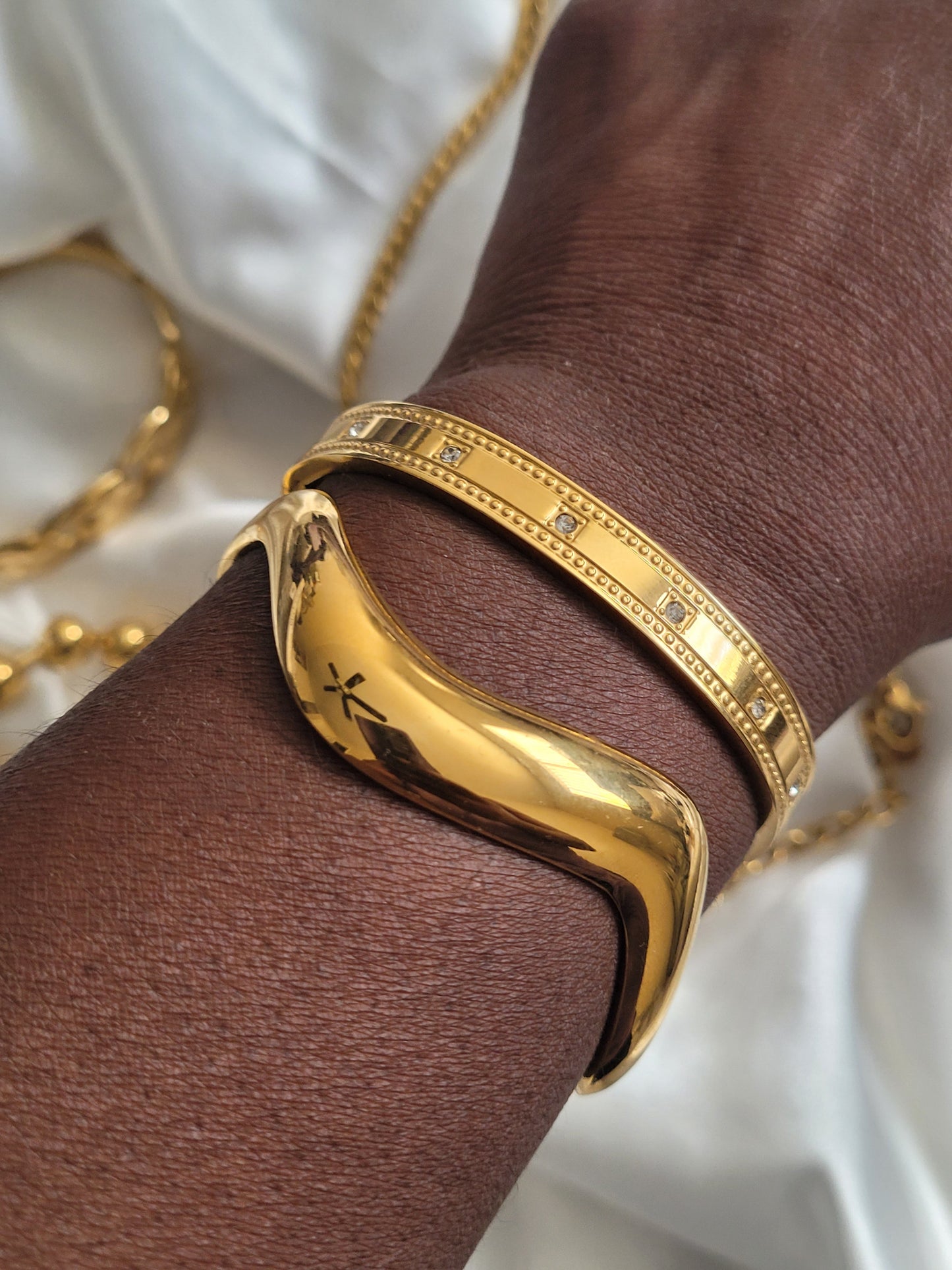 stainless steel open cuff bracelet on a wrist with a white background