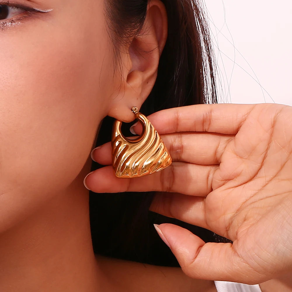 18K PVD Gold earring being held near an ear