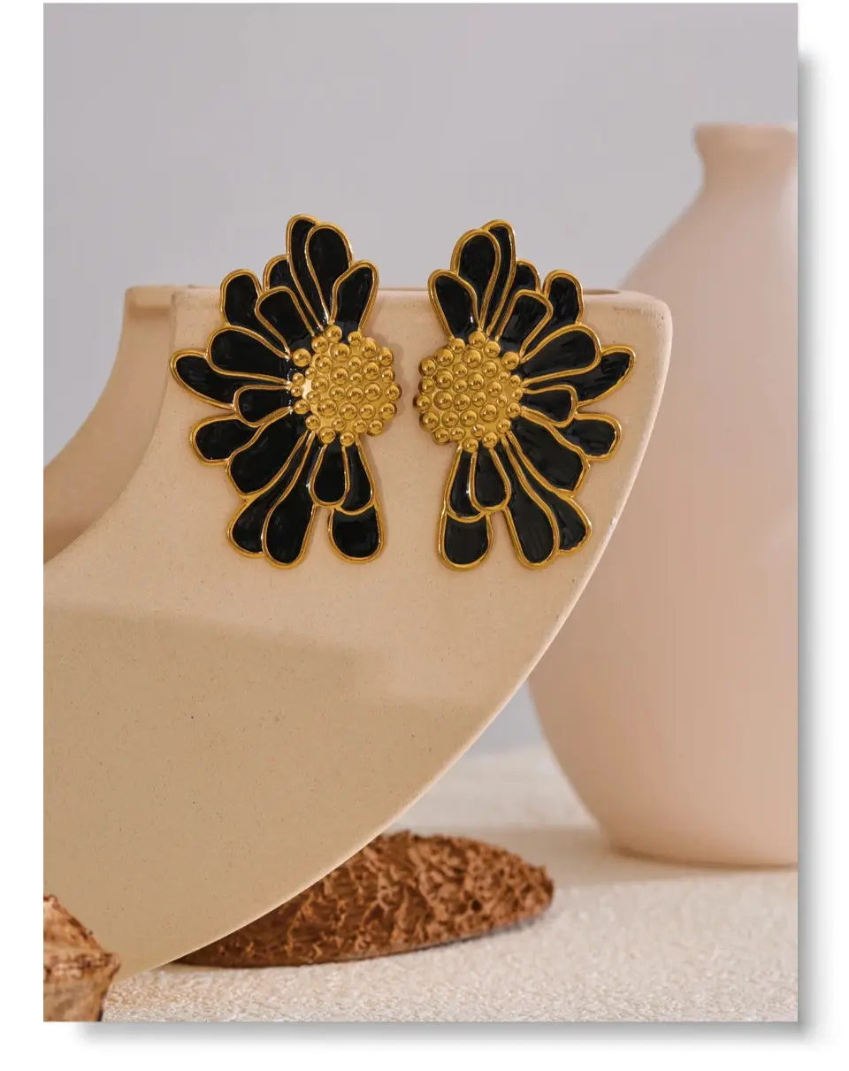 Studio shot of a pair of gold and black sunflower earrings, highlighting the detailed enamel work and the high-polish shine.