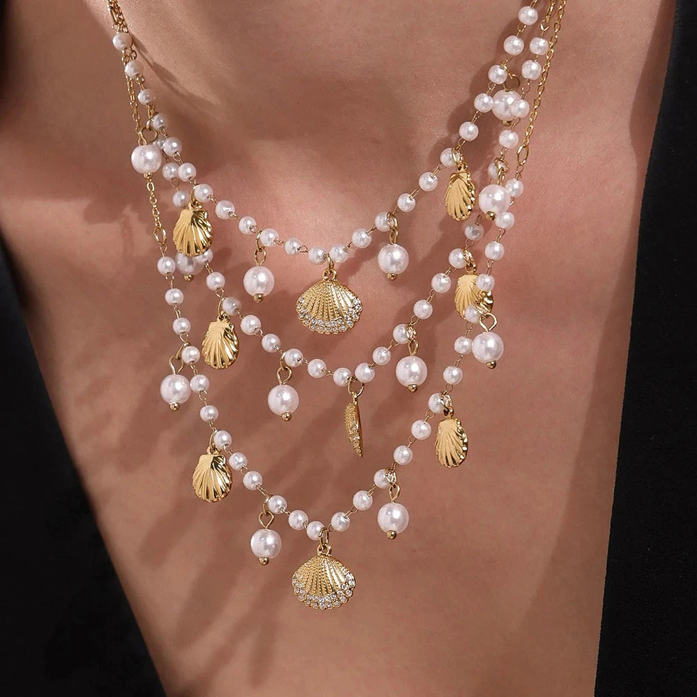 Pearl necklace with gold shell pendants on a person's neck