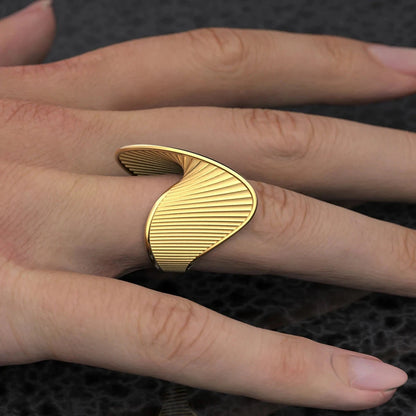 18K PVD Gold-Plated ring on a finger against a textured black background. Geometric textured gold ring