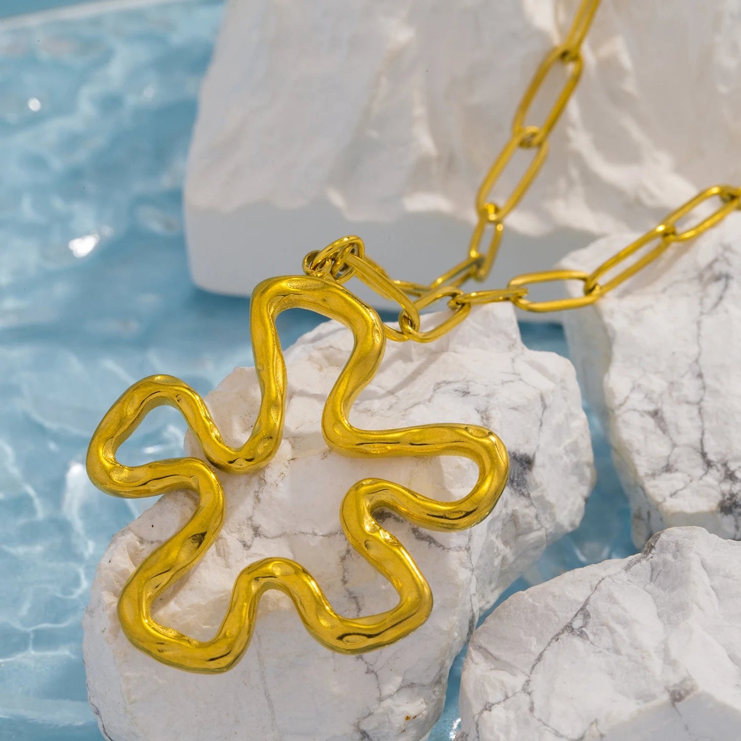 Gold floral charm necklace laid flat — vintage casting hollow flower pendant design